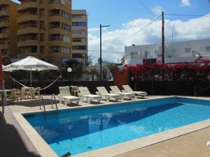 a swimming pool with lounge chairs and an umbrella at Apartamentos Es Cantó in Playa d'en Bossa
