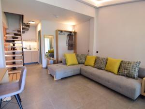 a living room with a gray couch and yellow pillows at Aloe The Green Suites - Nikiti Halkidiki in Nikiti