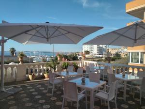 a patio with tables and white chairs and umbrellas at Antico Palazzo Spinola in Gallipoli