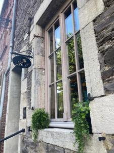 una ventana en el lateral de un edificio de ladrillo con plantas en Le Huit en Fumay