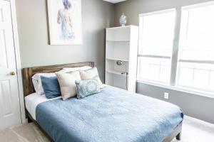 a bedroom with a bed with blue sheets and pillows at University Escape with hot tub and fire pit in University Place