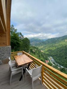 einen Holztisch und Stühle auf einem Balkon mit Aussicht in der Unterkunft Vadi dağ evi bungalov in Çamlıhemşin