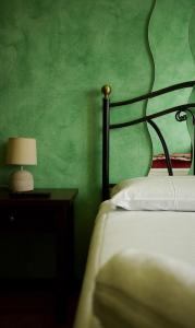 a bedroom with a green wall with a bed and a lamp at Locanda Al 5 - Bed & Beer in Lainate +20 photos