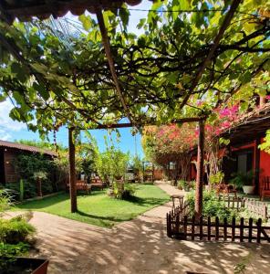 a garden with a fence and trees and flowers at Pousada Vila Sol in São Miguel do Gostoso