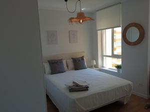 - une chambre avec un lit blanc, un miroir et une fenêtre dans l'établissement HH Apartamento Algarrobo costa, à Algarrobo-Costa