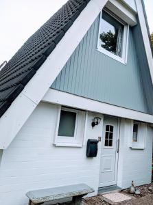 ein weißes Haus mit einer weißen Tür und einer Bank in der Unterkunft Dat lütte Strandhuus in Cuxhaven