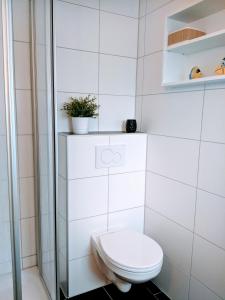 a white bathroom with a toilet and a plant at Dat lütte Strandhuus in Cuxhaven