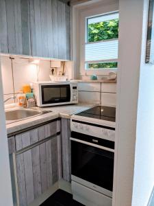 a kitchen with a stove and a microwave and a sink at Dat lütte Strandhuus in Cuxhaven