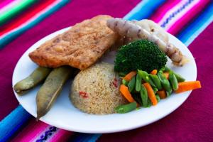 einen Teller mit Reis und Gemüse auf dem Tisch in der Unterkunft Hospedaje y Restaurante Saywa in Llachon