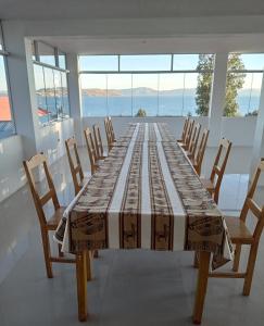 a long table in a room with chairs and windows at Hospedaje y Restaurante Saywa in Llachon