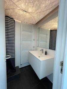 a bathroom with a white sink and a mirror at Lugano Lake, nido del cigno in Oria