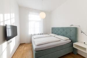 a bedroom with a blue couch and a television at Apartments Leonardo in Bolzano