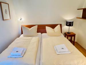 2 Betten in einem Zimmer mit weißer Bettwäsche und Handtüchern in der Unterkunft Villa Schlossbauer - Ferienwohnung 13 in Heringsdorf