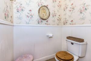 a bathroom with a toilet and a clock on the wall at Binky's Summer Afternoon in Fredericksburg