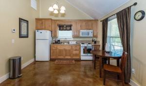 a kitchen with a table and a white refrigerator at Appian Way Celtic Cottage in Fredericksburg