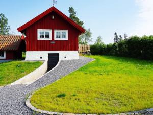a red building with a garage in a yard at 5 person holiday home in Mell sa in Mellösa