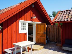 een rode schuur met een deur en een bank op een dek bij 5 person holiday home in Mell sa in Mellösa