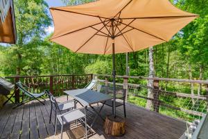 a table and chairs on a deck with an umbrella at Gîte Nature in Vitrac-sur-Montane