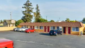 a building with cars parked in a parking lot at Hollister Inn in Hollister