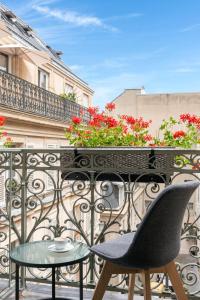 une chaise et une table sur un balcon fleuri dans l'établissement Hôtel Aston, à Paris
