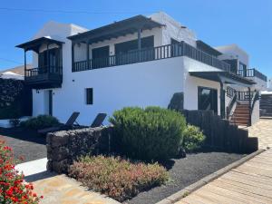 Casa blanca con balcón y algunos arbustos en Las Casitas Rusticas en La Asomada