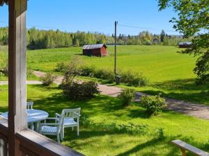 a porch with a table and chairs and a field at 7 person holiday home in J RBO in Åshammar