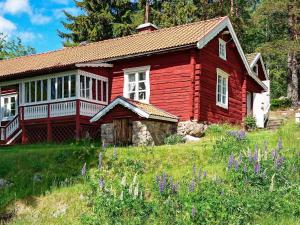 una casa roja en una colina con flores púrpuras en 7 person holiday home in J RBO, en Åshammar