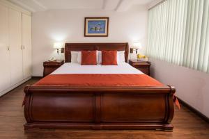 a bedroom with a large wooden bed with orange pillows at Hotel Cordero in Cuenca