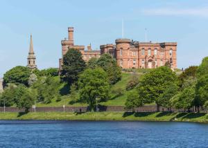 ein Schloss auf einem Hügel neben einem Wasserkörper in der Unterkunft Pinewood Cottage Apartment & B&B Inverness in Inverness