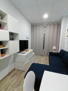 a living room with a blue couch and a tv at Apartamentos Sane in Noja