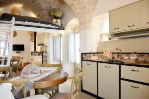 una cocina con armarios blancos y una mesa en una habitación en Alcova Cellini Bell'Italia, en Cisternino