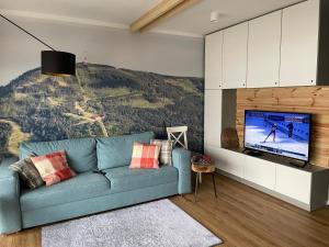 salon z niebieską kanapą i telewizorem w obiekcie Apartament Na Górce, sauna & jacuzzi w Szczyrku
