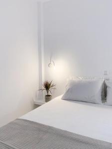 LULU - Self Catering Accommodation في مونيمفاسيا: غرفة نوم بيضاء فيها سرير ابيض ونبات