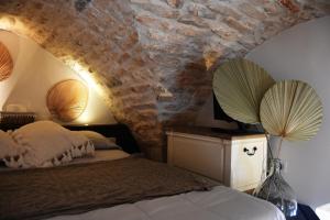 1 dormitorio con cama y pared de piedra en Alcova Cellini Bell'Italia, en Cisternino