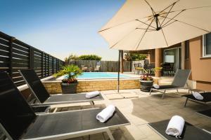 a patio with chairs and an umbrella and a pool at AS Apartmani "Chocolate" in Peroj