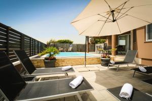a patio with chairs and an umbrella and a pool at AS Apartments Peroj in Peroj