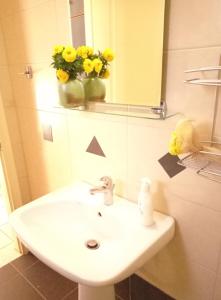 a bathroom sink with a mirror and a vase of yellow flowers at Evangelia House Sea View Apartments in Agia Pelagia