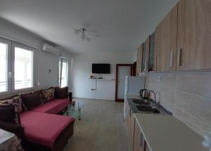 a living room with a red couch in a kitchen at Apartman G 60 in Meljine