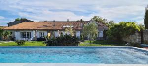 une maison avec une piscine en face d'une maison dans l'établissement Domaine des Prés de Joussac - Protocole sanitaire strict, à Jau-Dignac-et-Loirac