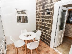 a white table and chairs in a room with a brick wall at Feathers Cottage in Haworth