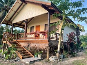 a house with a porch and stairs leading to it at Tavake Villa in Arutanga