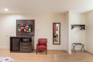 a living room with a red chair and a mirror at Red Roof Inn Houston - Willowbrook in Houston
