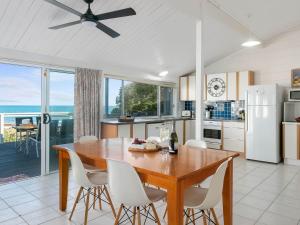 a kitchen with a wooden table and white chairs at Wave and See 53 Gold Coast Drive in Carrickalinga +23 photos