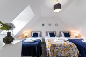 three beds in a room with blue and yellow sheets at KVM Bluebird House for large groups by KVM Serviced Accommodation in Peterborough