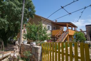 ein Haus mit einem gelben Zaun davor in der Unterkunft By Dinka in Ilovik