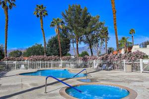 a swimming pool in a courtyard with palm trees at Red Roof Retreat in Rancho Mirage