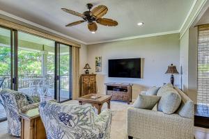 a living room with two chairs and a flat screen tv at Kapalua Golf Villas 16V3 in Kahana