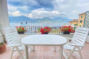 een witte tafel en stoelen op een balkon met uitzicht op de oceaan bij Casa Anna with Lake View in Menaggio