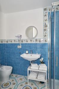 W wyłożonej niebieskimi kafelkami łazience znajduje się umywalka i toaleta. w obiekcie Malafemmena Guest House w mieście Capri