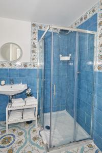 a blue tiled bathroom with a shower and a sink at Malafemmena Guest House in Capri